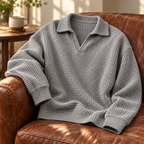 Grey waffle knit polo laid over the arm of a leather chair